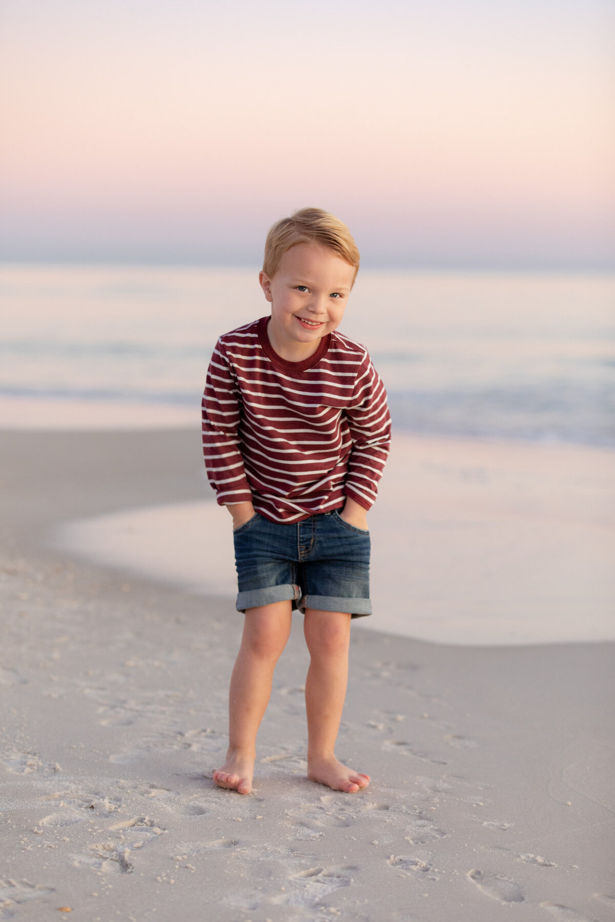 A small boy smiling with his hands in his pockets