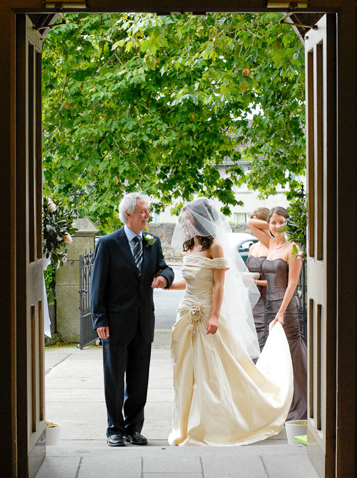 bride wearing a warm ivory, raw silk, a-line wedding dress looking at her father before walking up the aisle