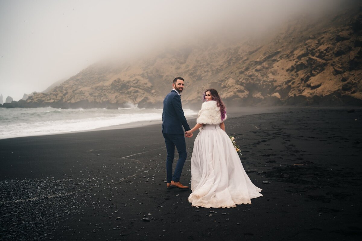 Hand in hand, this couple takes a leisurely stroll along the captivating black sands of an Icelandic beach, creating memories of love against a unique backdrop.
