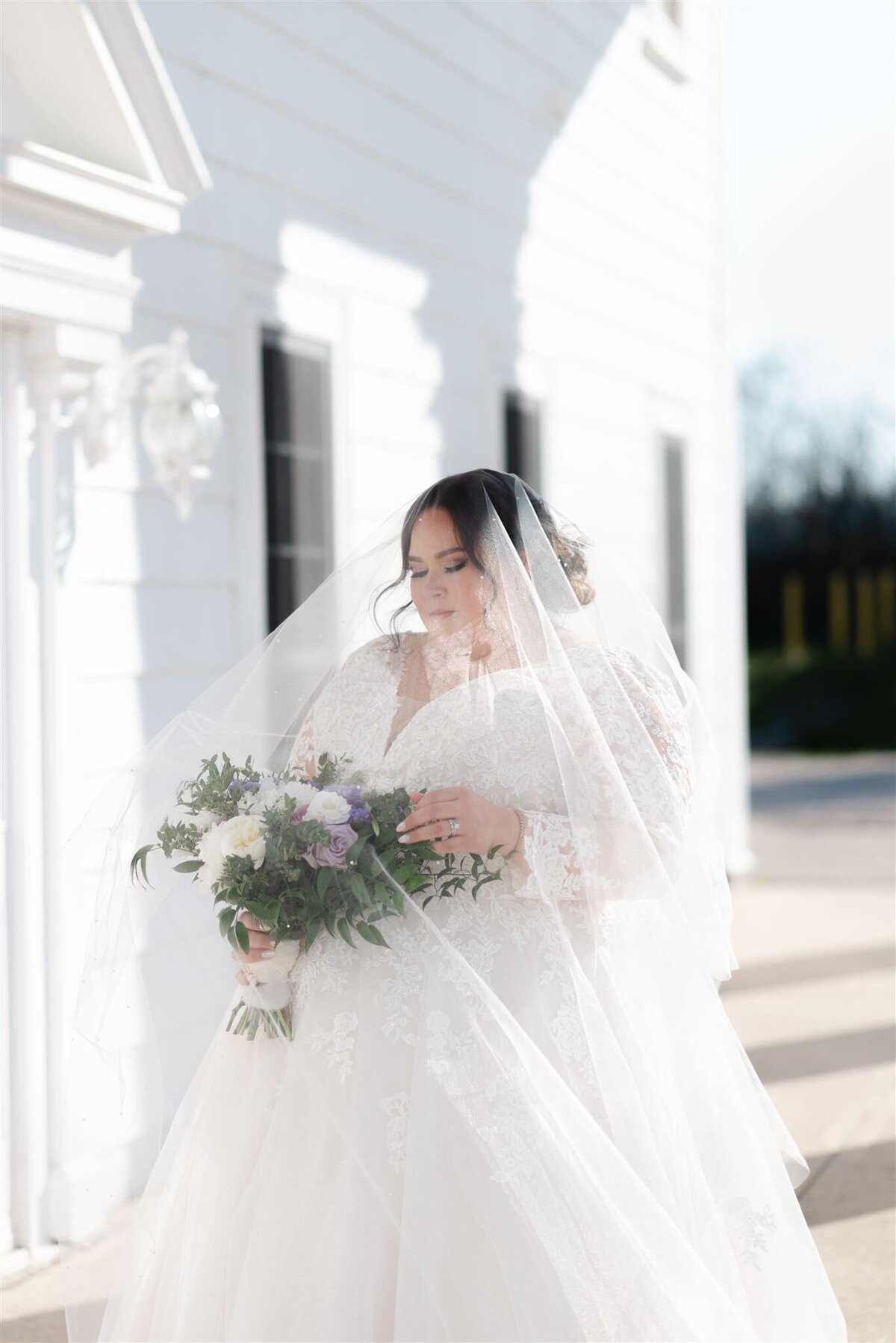 Beautiful Bride with her Veil over her looking at her wedding flowers