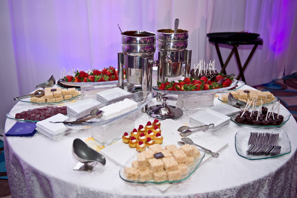 Wedding dessert table that has cakes, brownies, cupcakes and fruits