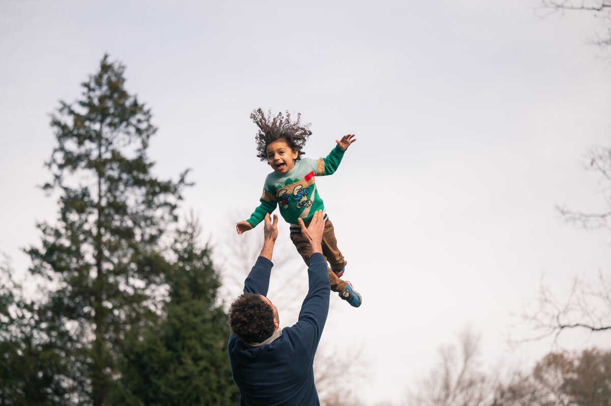 Dad tossing son in the air, son's hair flying