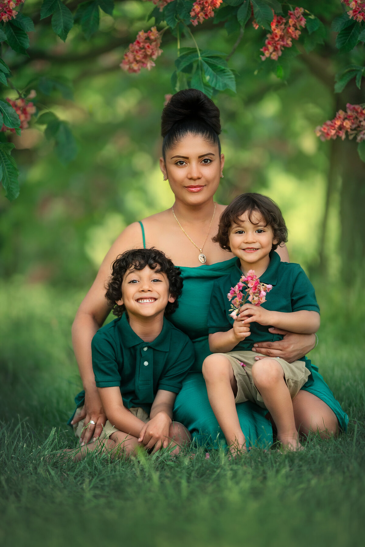 Hispanic mom and her two kids dressed in green  clothes  holding chestnut tree blossoms