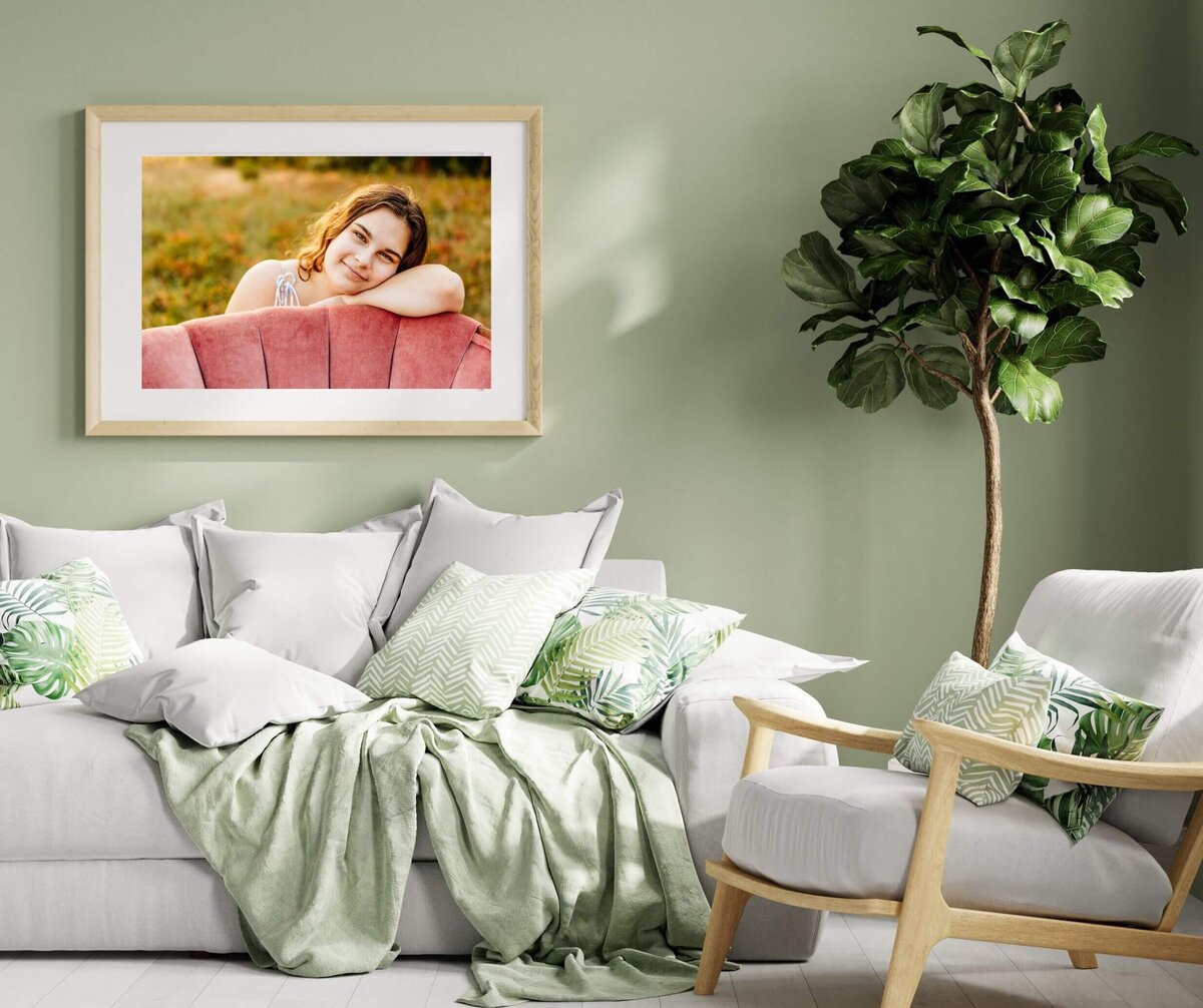 photo of a senior girl leaning on a pink chair being displayed on a green living room wall in Green Bay