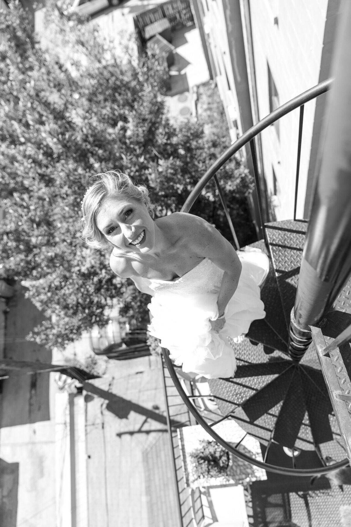A bride looks up from a fire escape at a Chicago city wedding.