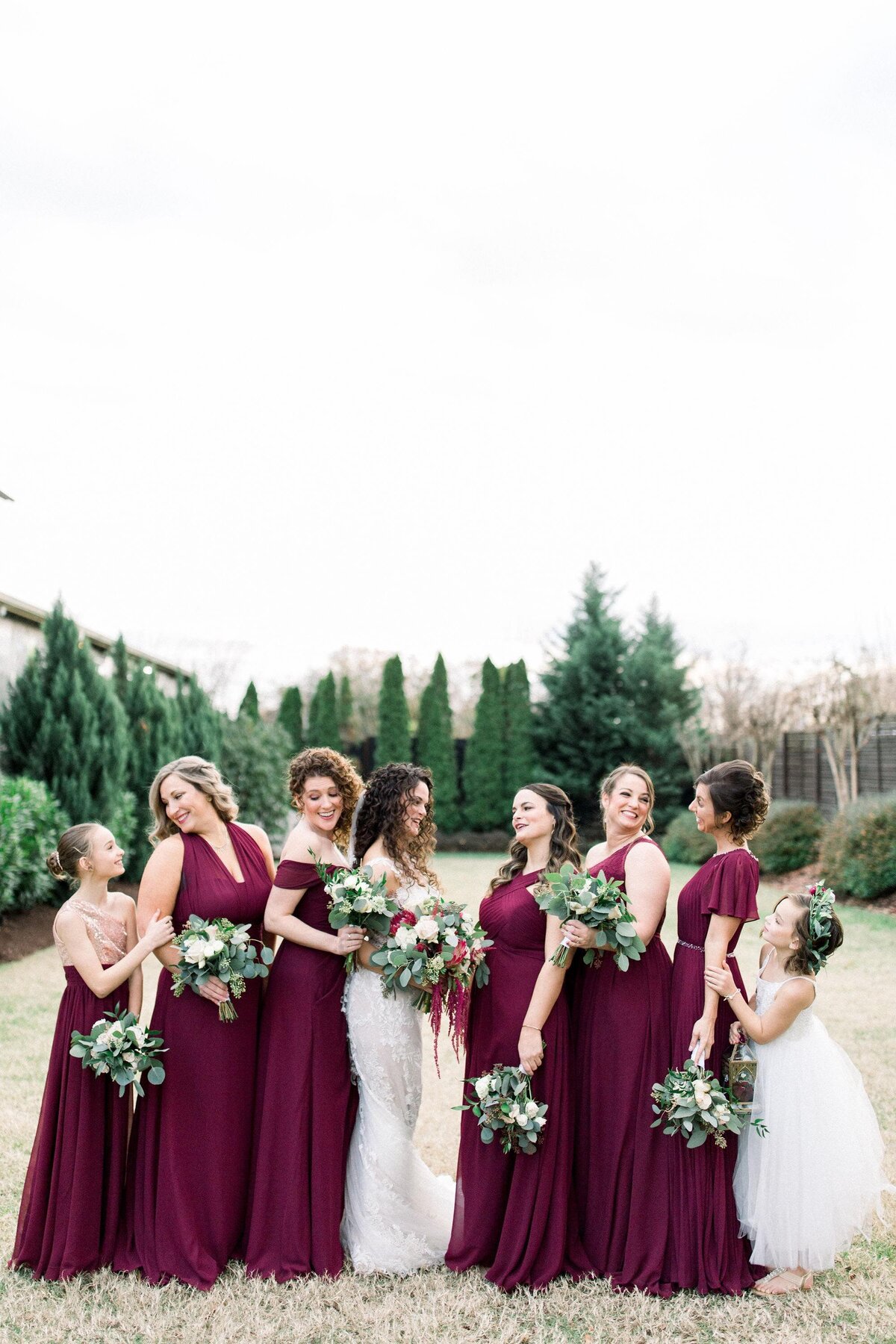 bride and her bridesmaids wearing burgundy dresses holding bouquets in white and burgundy