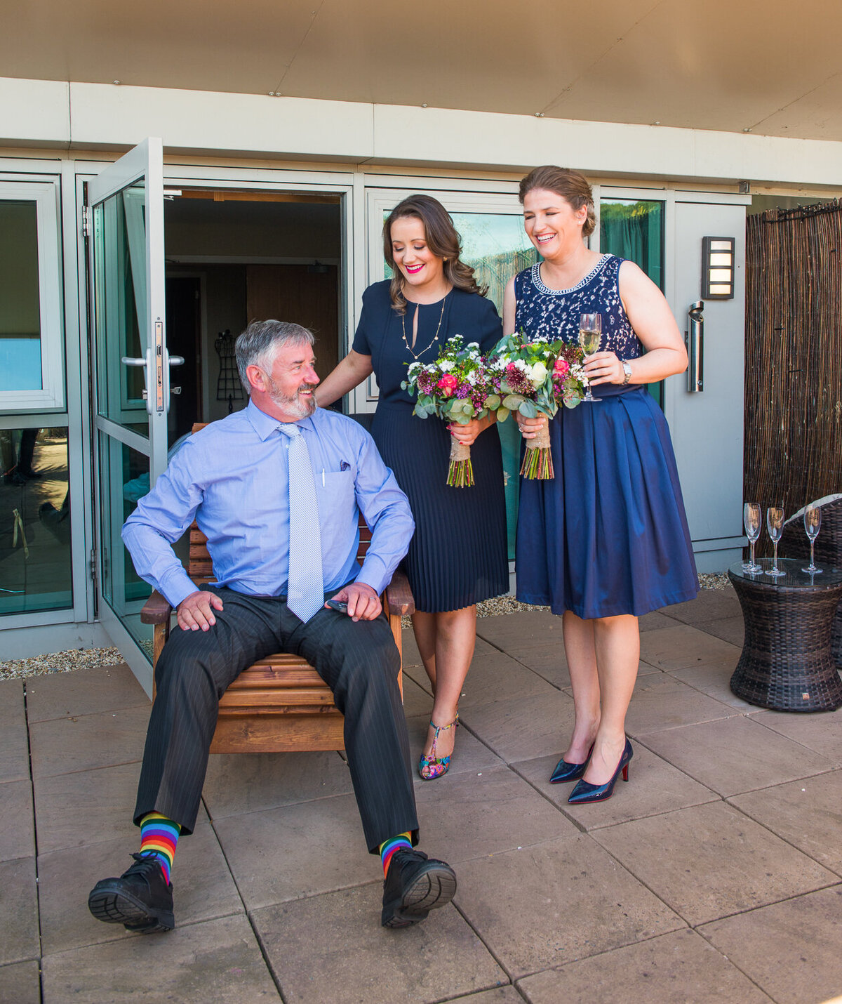 Two brides looking at dad's rainbow socks