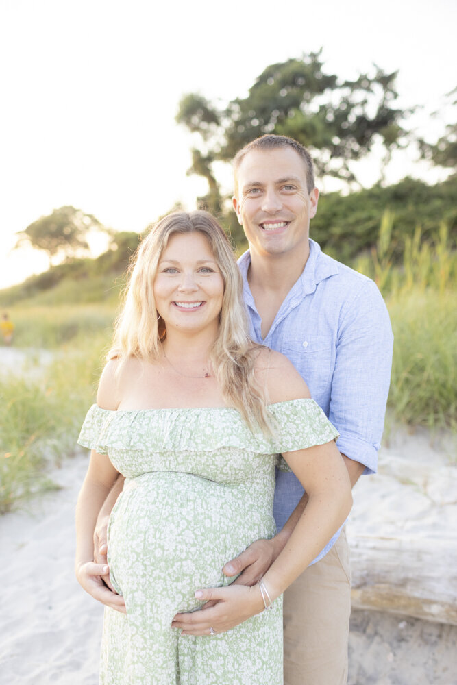 pregnant momma and husband pose on the beach