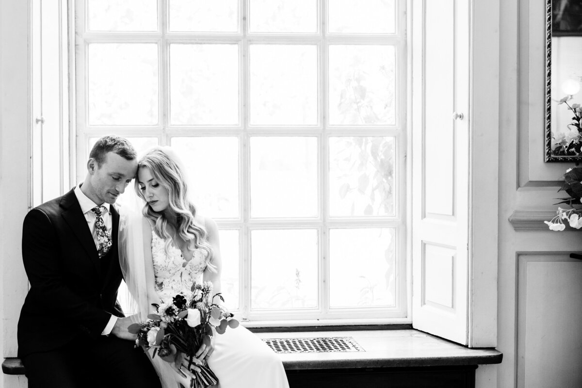 Bride and groom sitting in window at gosfield hall