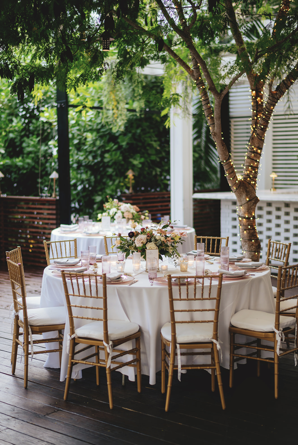 Bamboo chairs surround  circular tables at elegant outdoor Florida wedding reception at Holly Blue