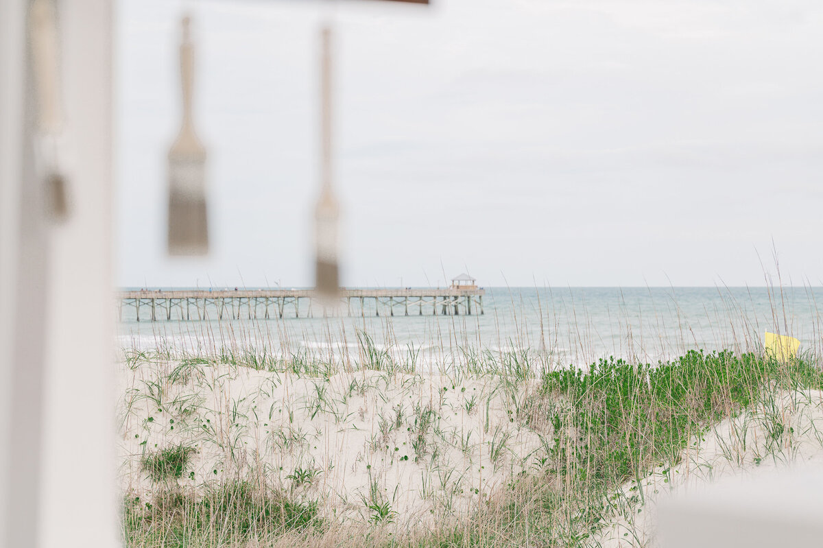 A beach pier in the distance on a wedding day by JoLynn Photography