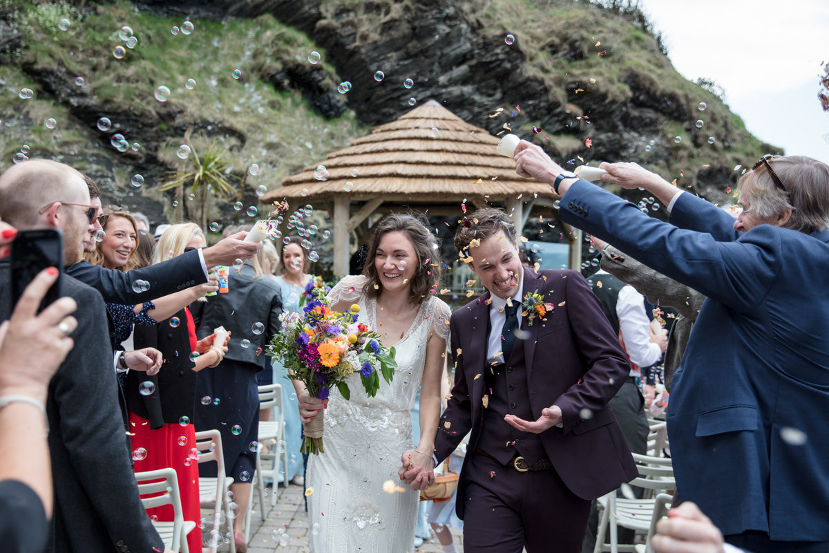 Walking down the aisle with confetti at Tunnels Beaches Devon