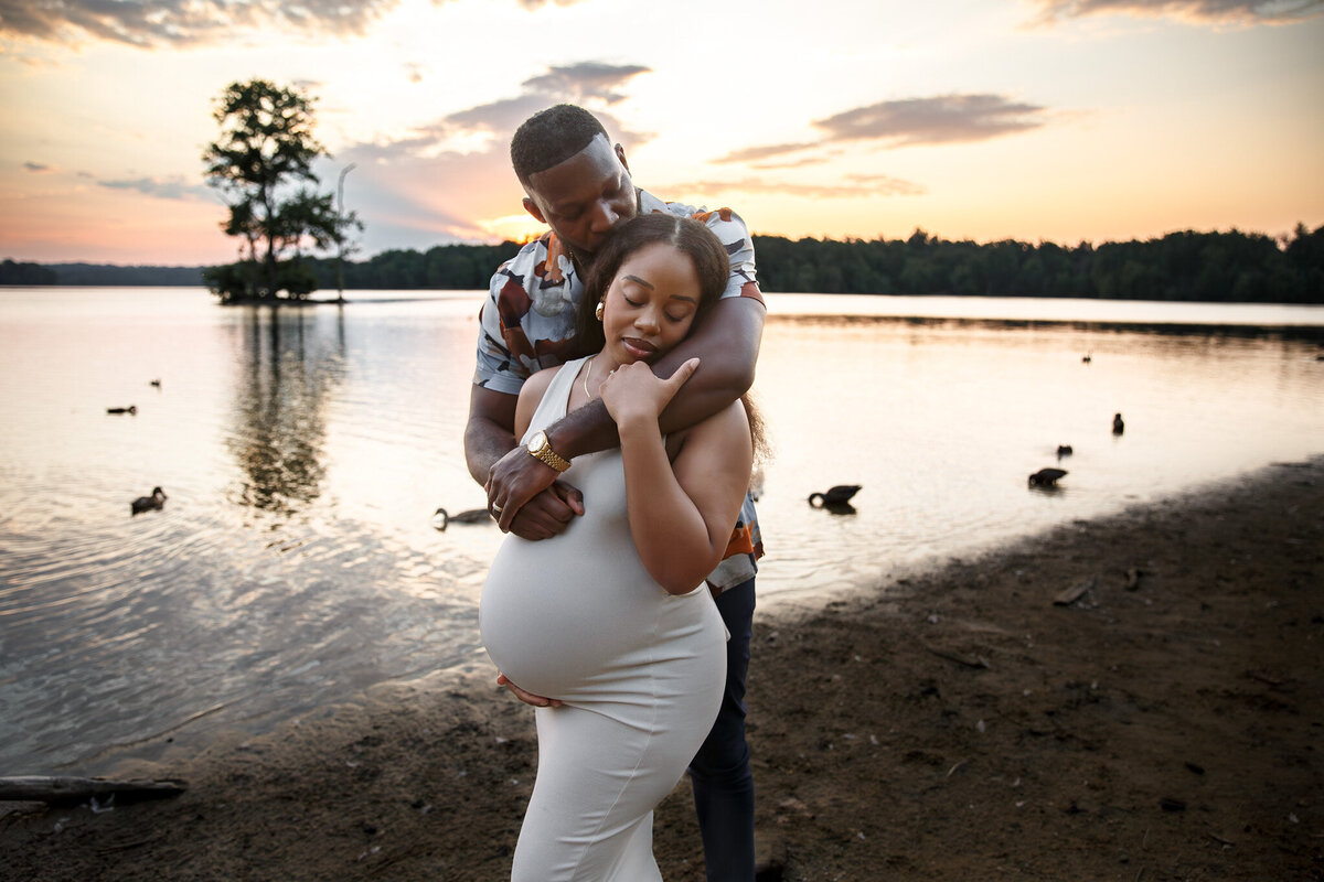 A couple embraces during their Loch Raven Reservoir maternity photos.