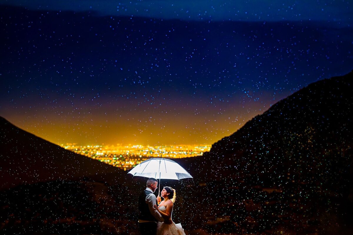 bride and groom under an umbrella with el paso city lights i