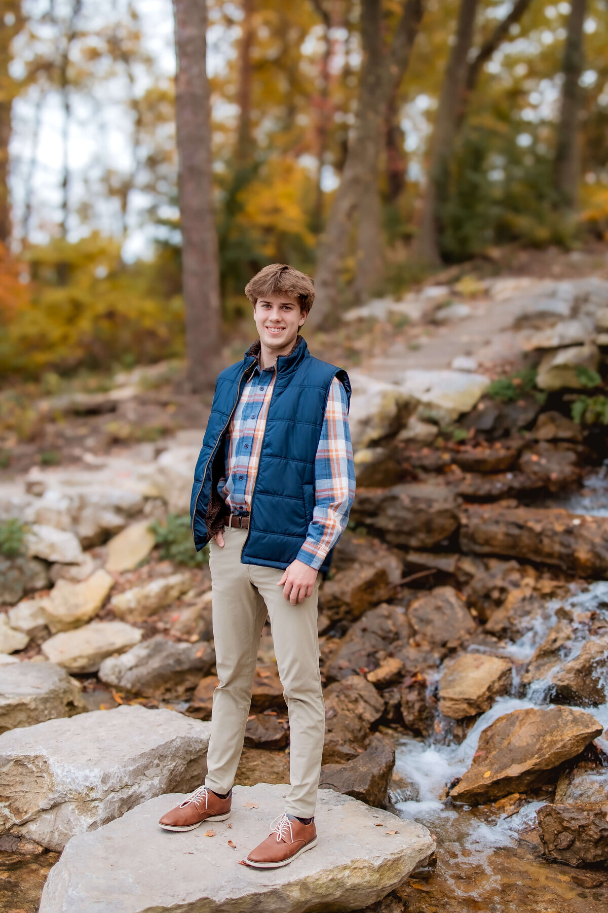 A handsome senior boy is posing for his senior portraits in Forest Park.