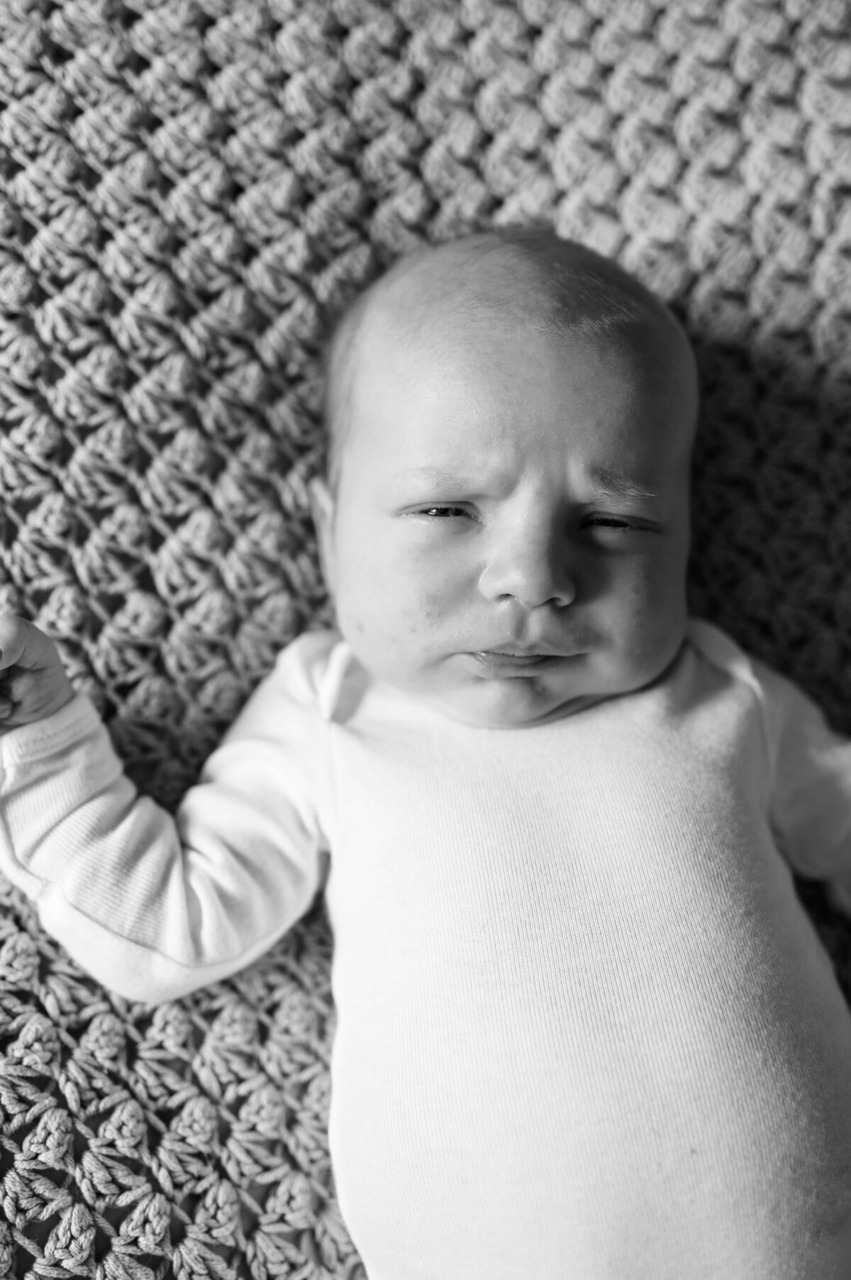 A black and white image displays a sweet baby making a grumpy face at Virginia family photographer, Erin Winter