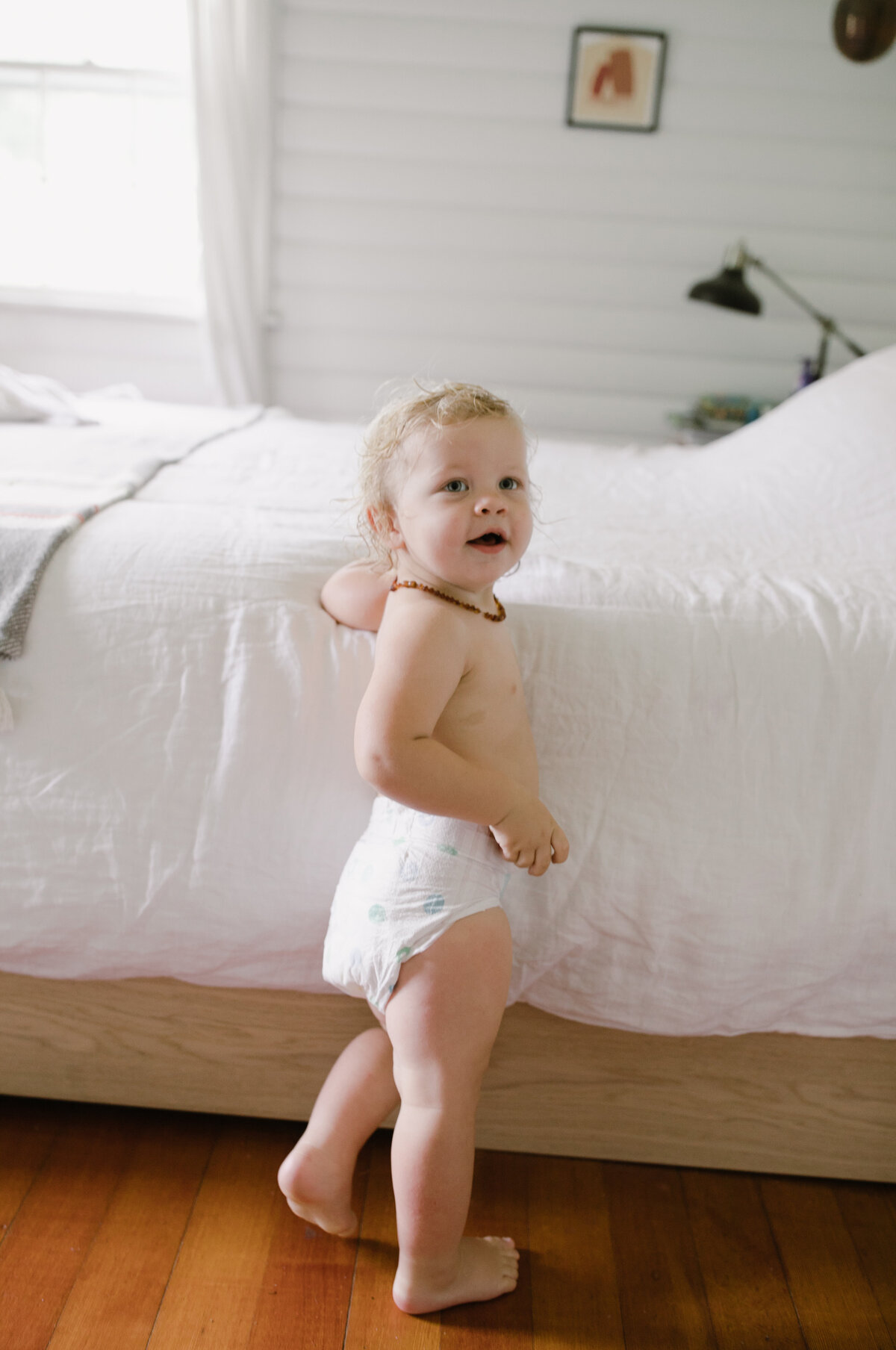 Baby in diaper by a bed at Austin family photo session