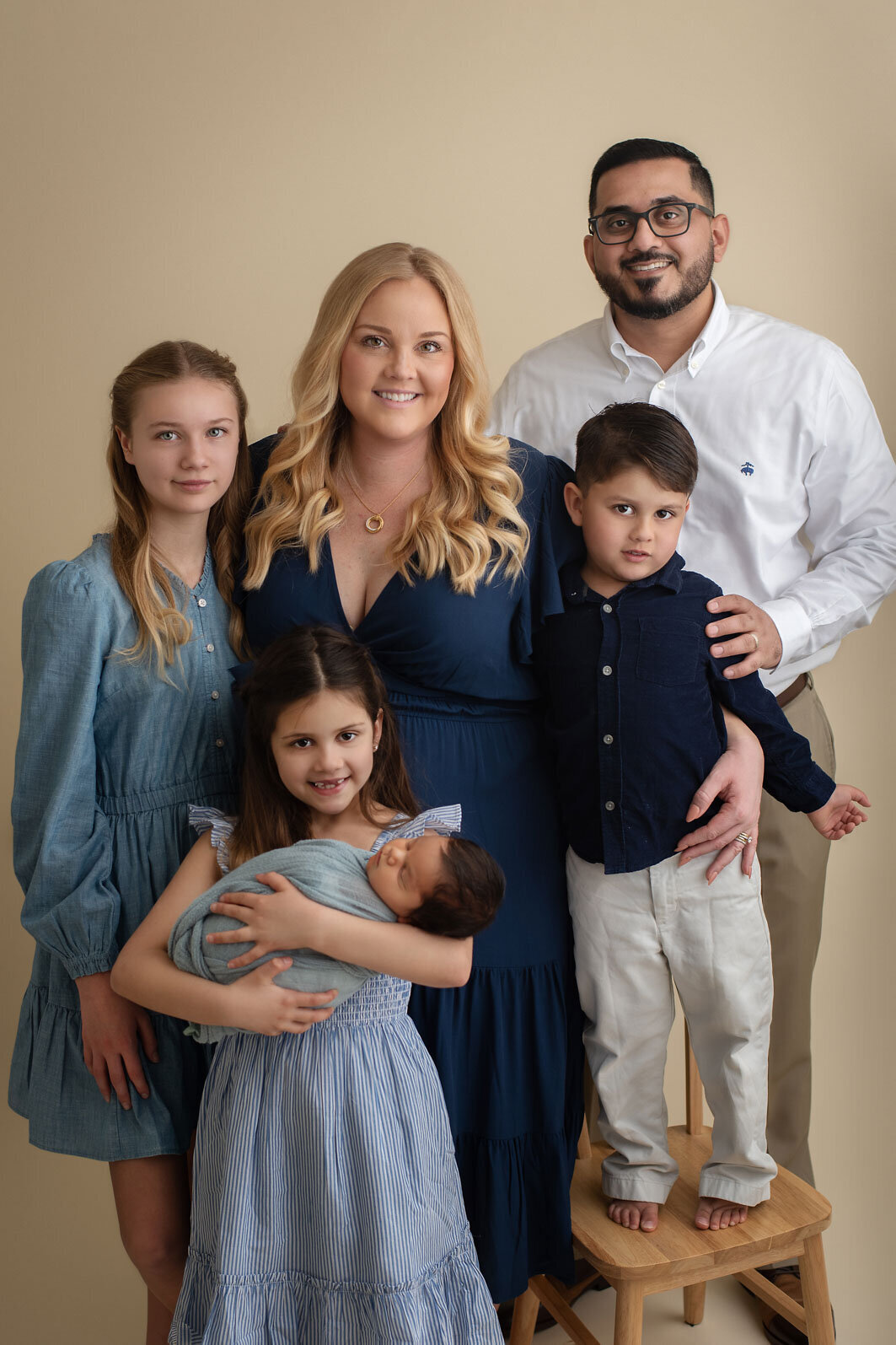 family of 6 looking at camera and smiling at baby's newborn photo session