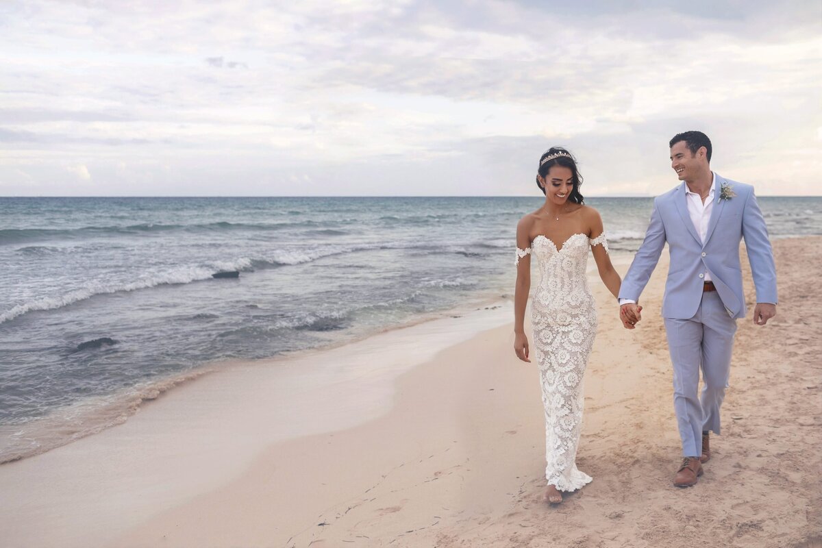 Bride and groom walking on beach after ceremony at  Riviera Maya wedding.