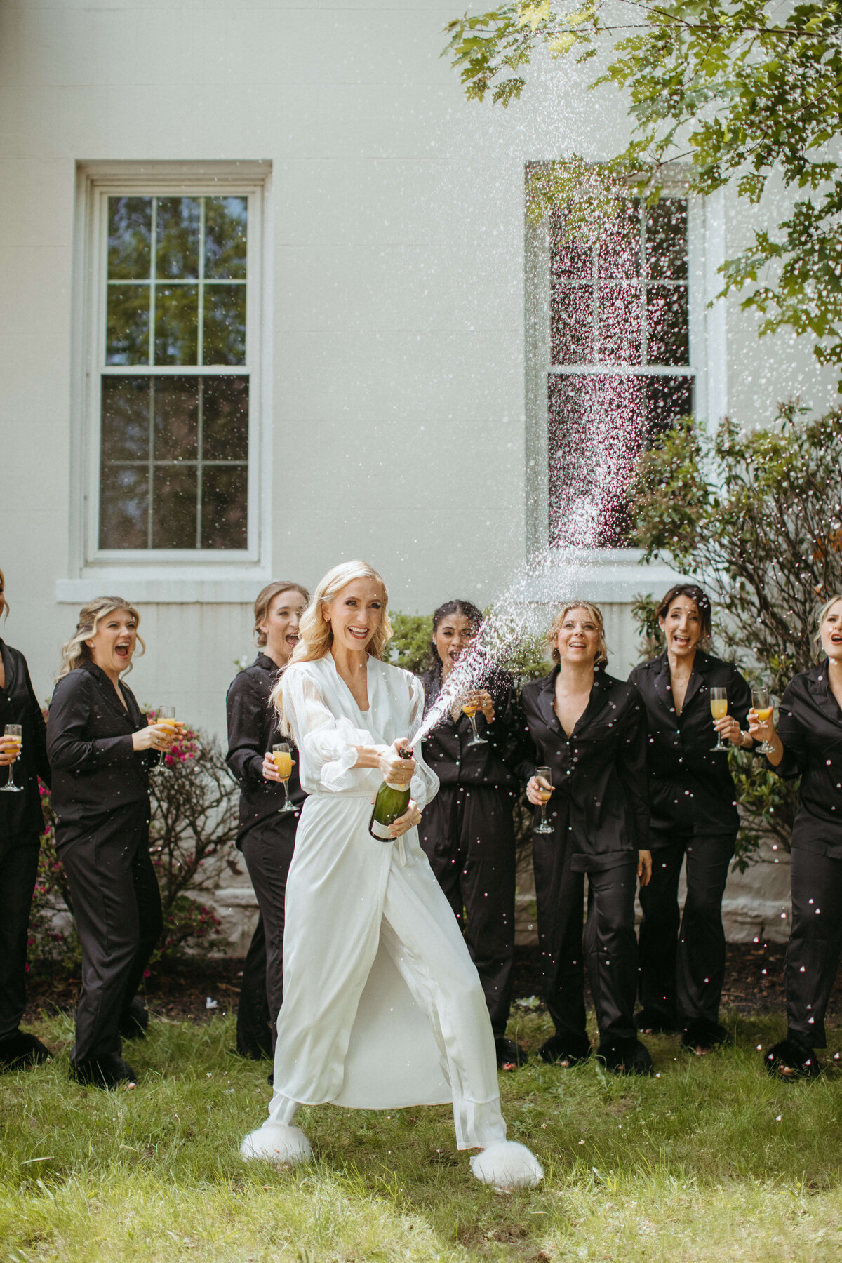 Bride holding a spraying bottle of champagne