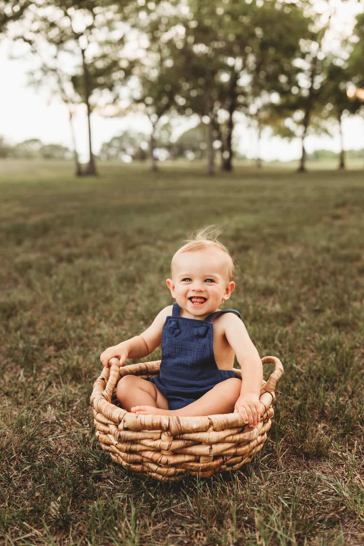 baby boy sits in wicker basket.