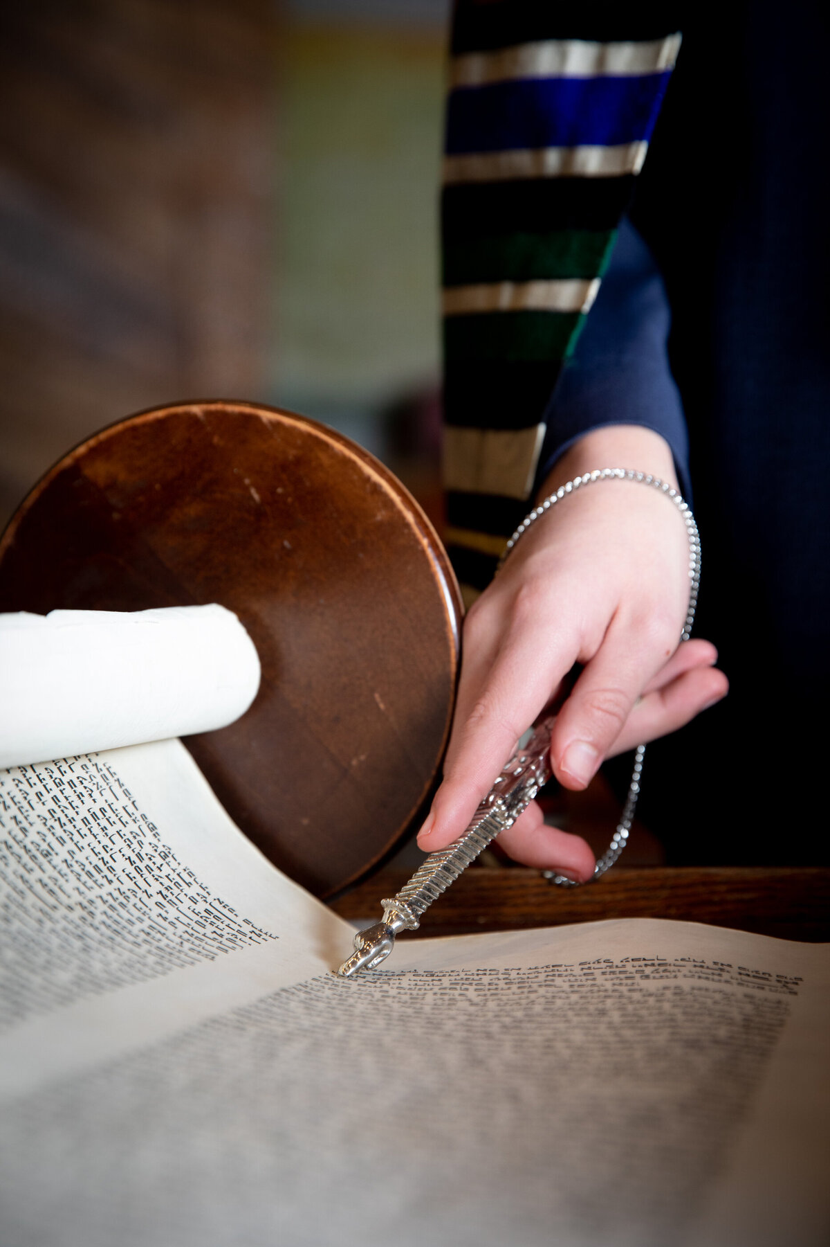Detail shot of a hand with a yad pointing to the Torah scroll bar New York mitzvah photographer Milestone Images