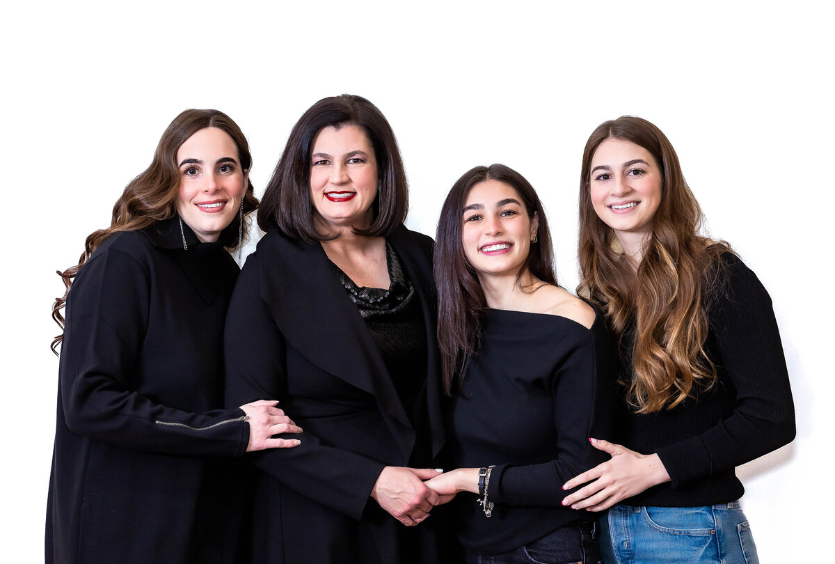 Mother with 3 daughters all wearing black tops and smiling at the camera.