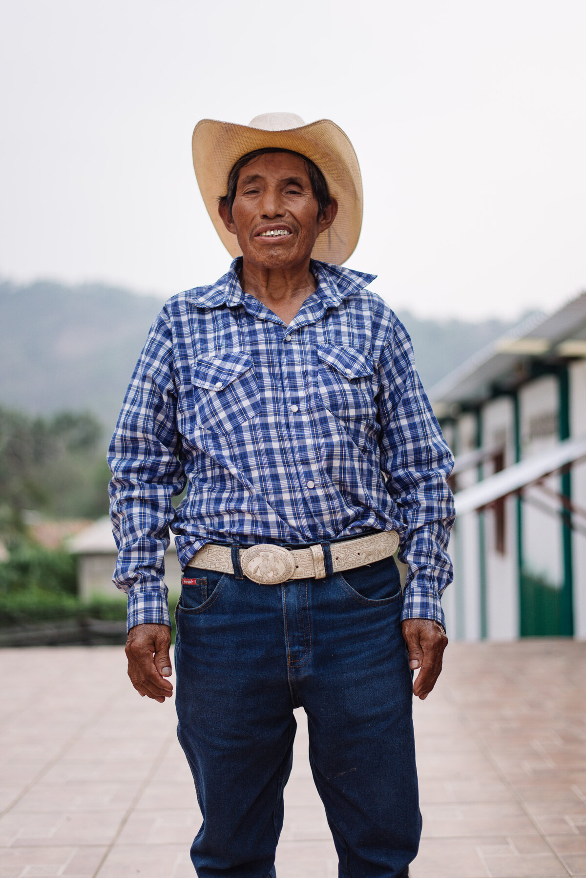 coffee farmer looks into gaze of camera wearing blue jeans and checkered shirt for Food 4 Farmers no profit