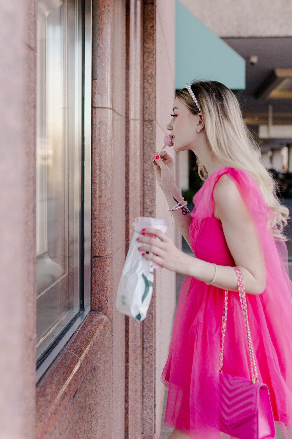 barbie model in pink tulle dress and pink purse holds starbucks coffee and cake pop in a breakfast at tiffany's inspired pose