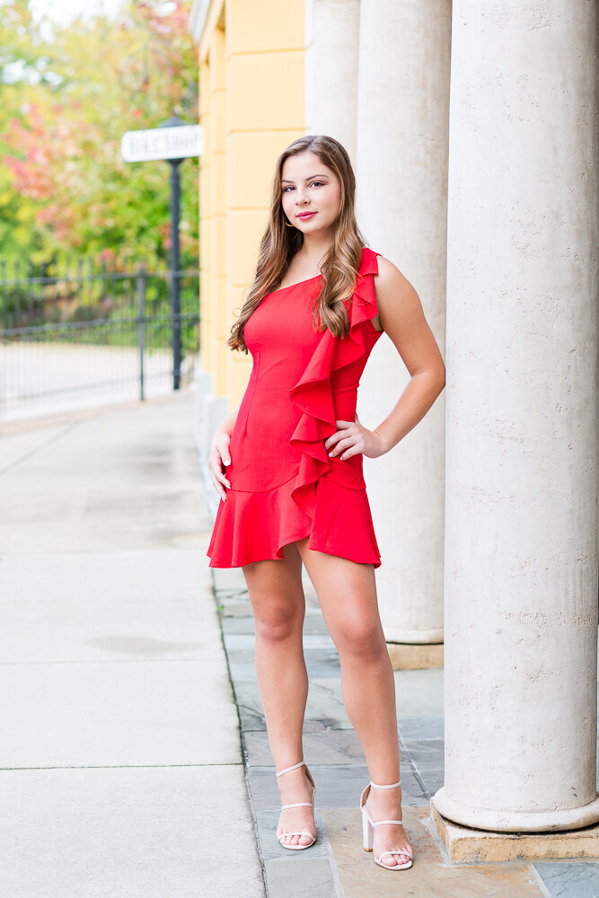 High school girl wearing a short red dress posing at LaFayette Village.