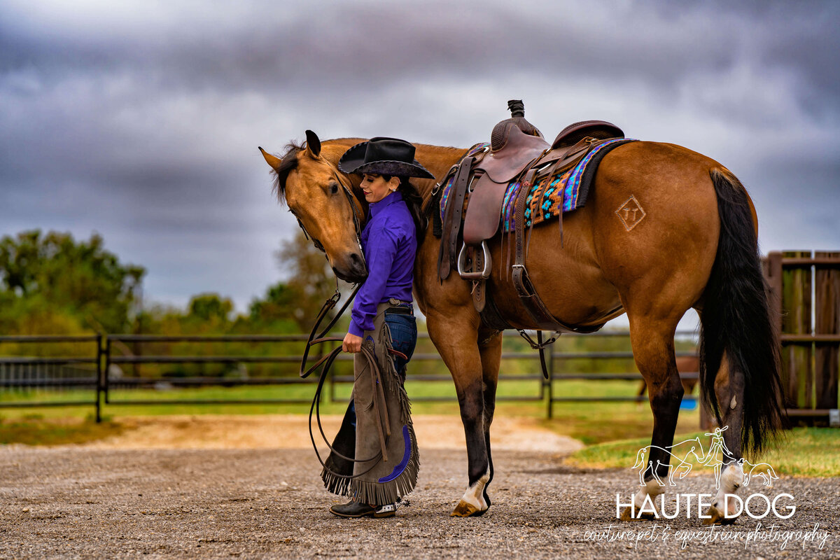 Female equestrian stands with a Quarter Horse under stormy sky, both facing away from the camera.