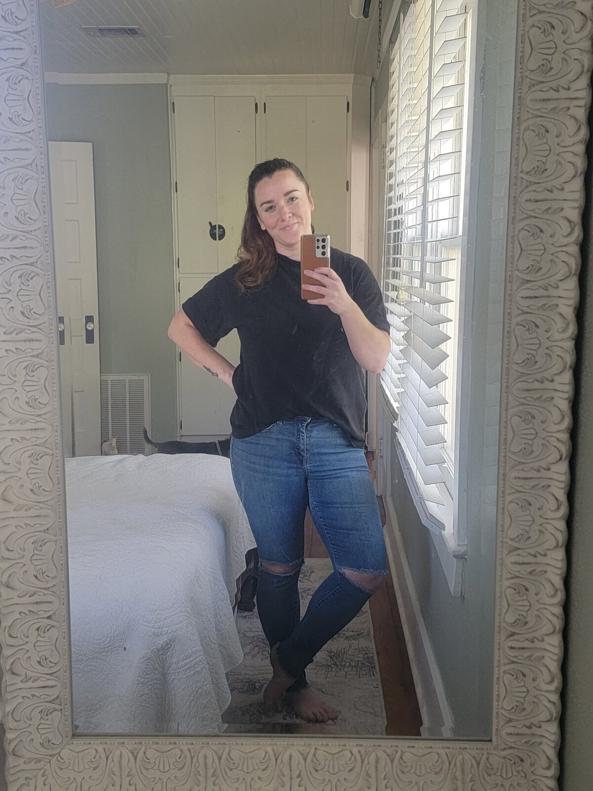 Brittney, posing in bedroom mirror in casual phone selfie
