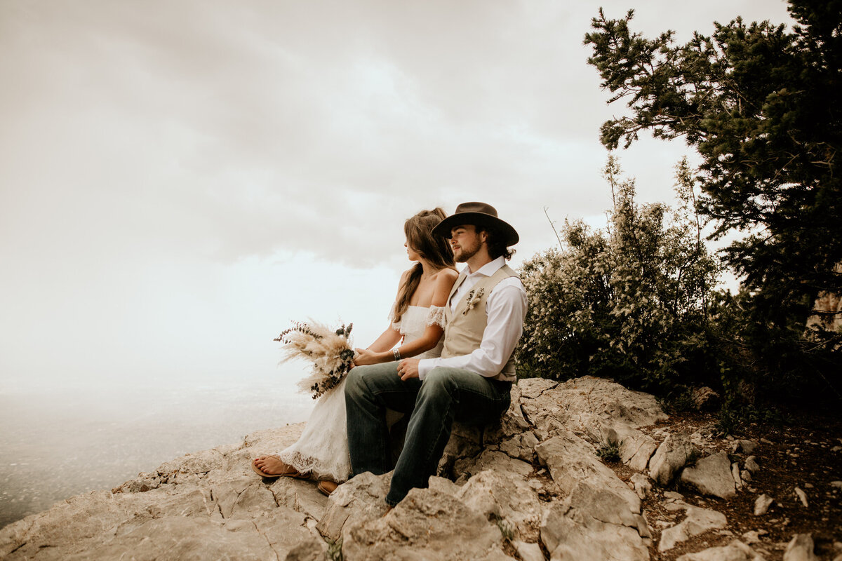 bride and groom sitting together at the Sandia Peak looking down at the city of Albuquerque