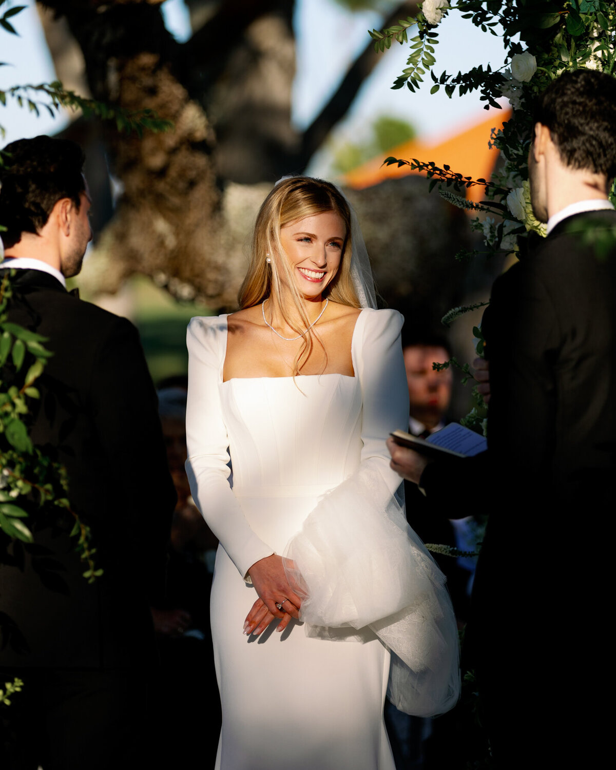 Bride standing in full sun and smiling during her Longboat Key Club wedding ceremony.