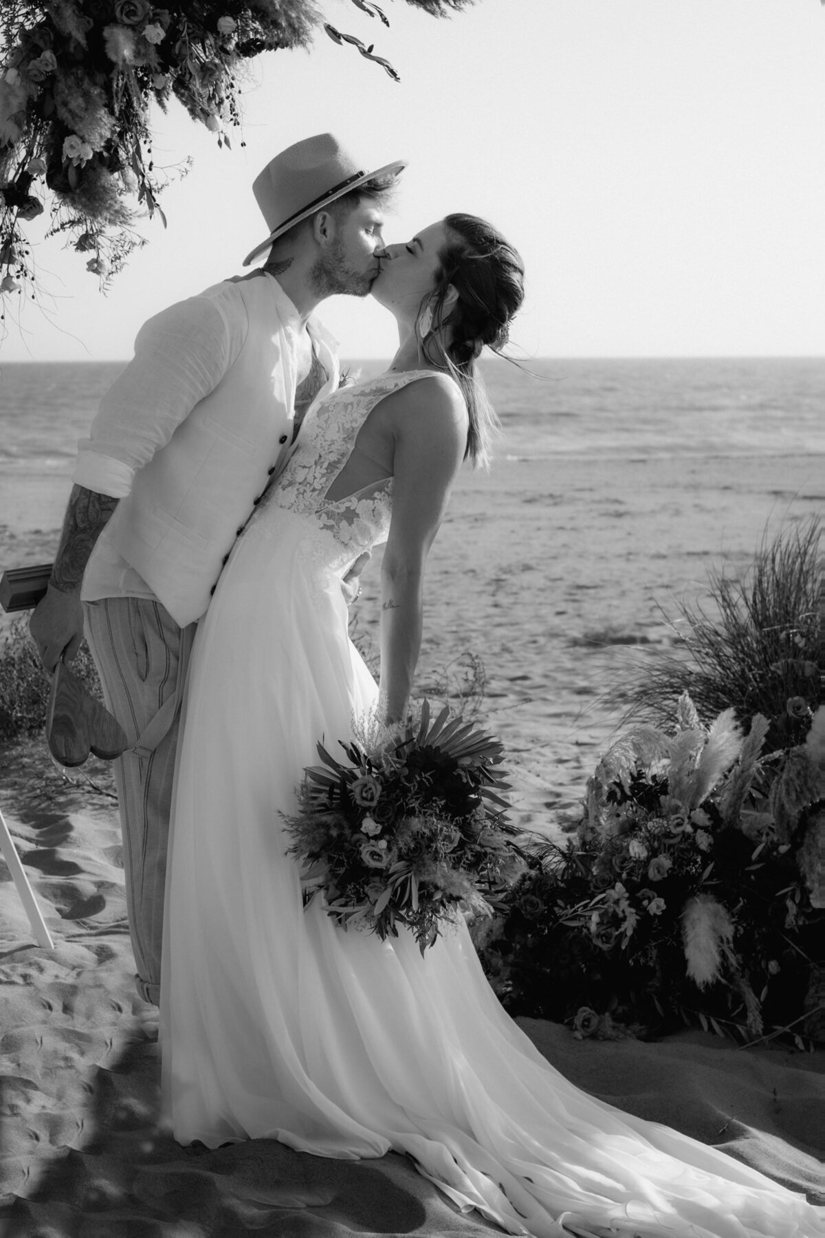Die Braut neigt sich leicht nach hinten, als der Bräutigam sie liebevoll küsst.