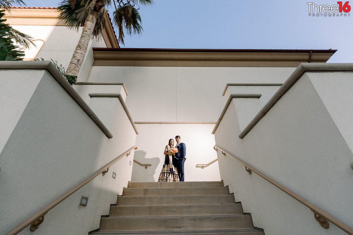 Bride and Groom stand together at the top of a long stairwell before heading down