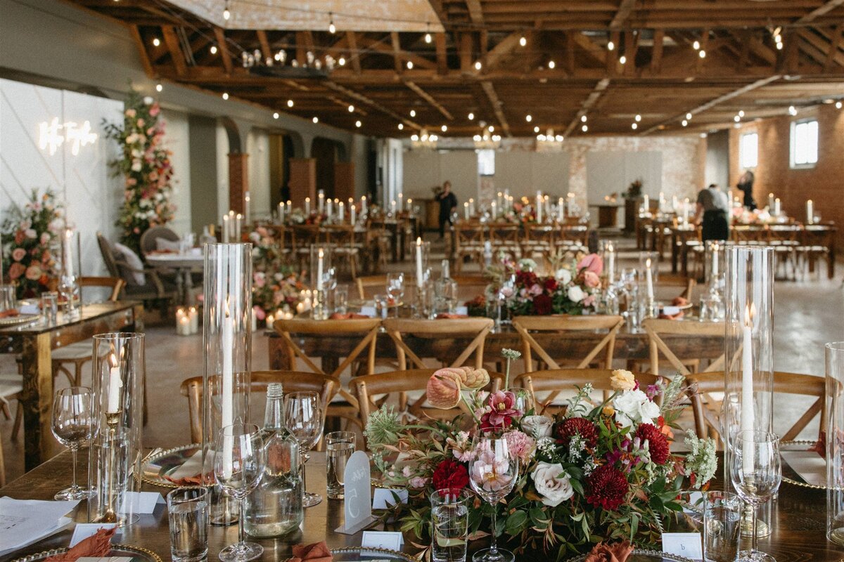 Colorful wedding table decor with burnt orange napkins, crimson,, white and pink florals