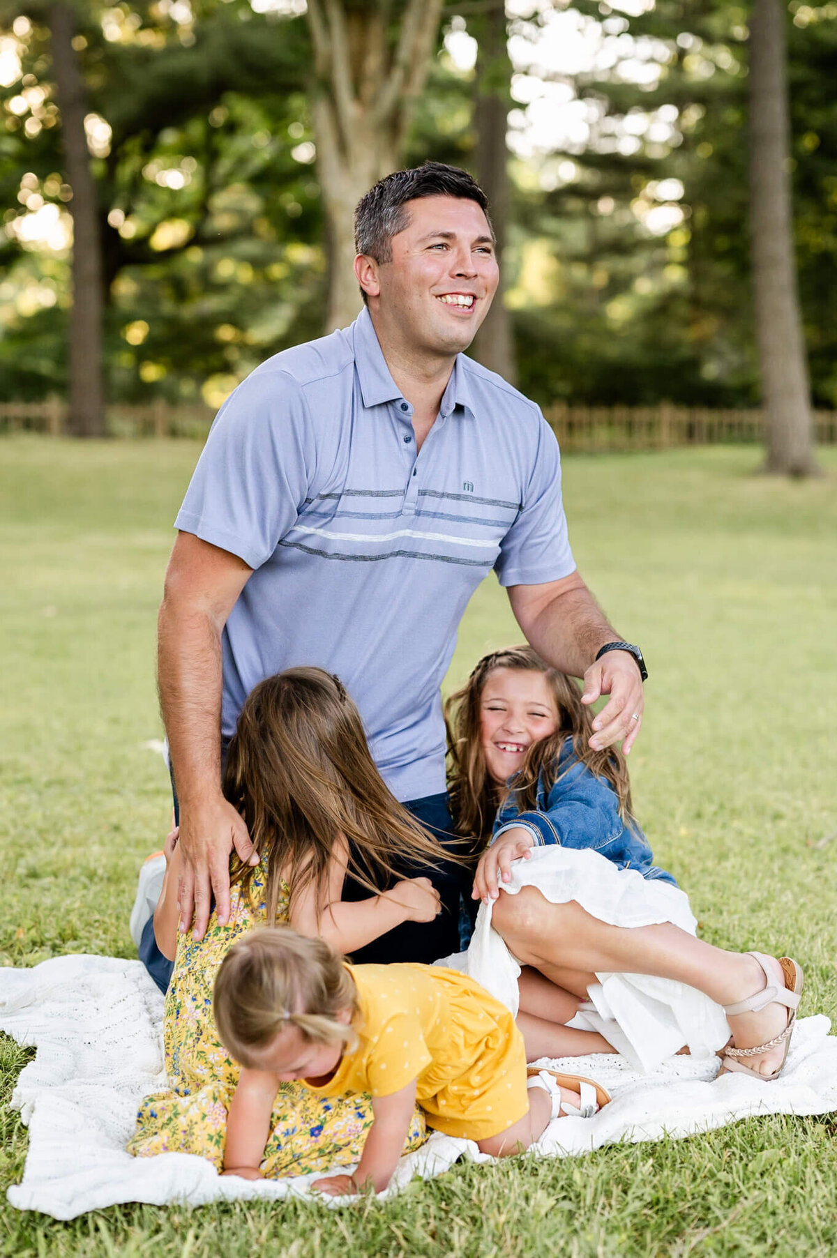 Dad laughing at daughters all around him at relaxed family session near St. Charles, IL.