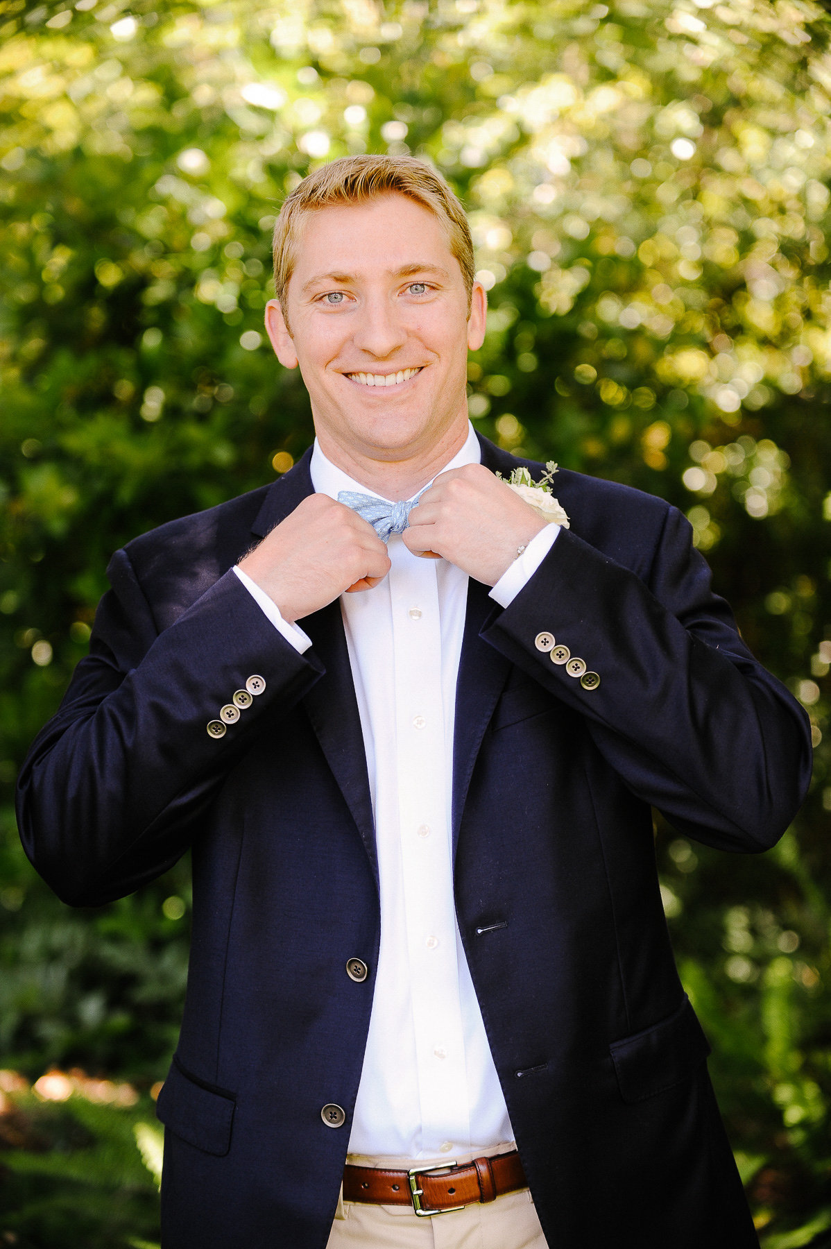 A groom tying his bowtie.
