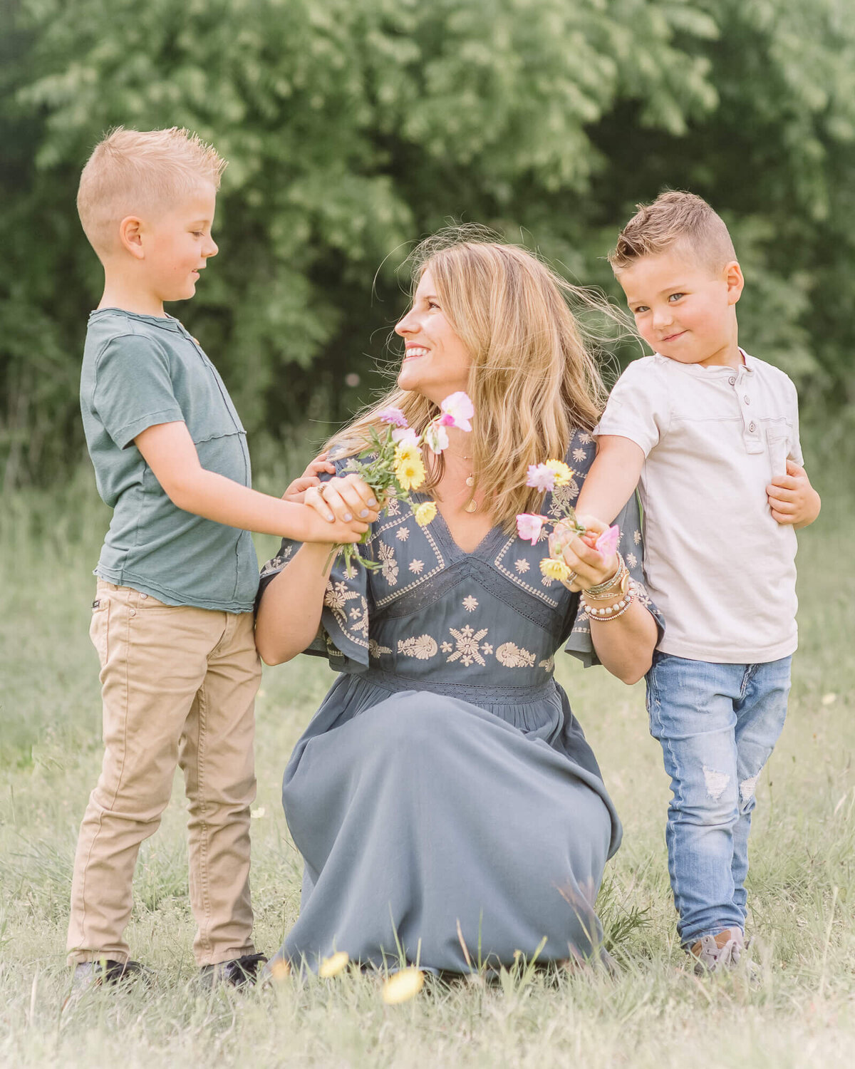 beautiful mother getting flowers outdoors from her adorable young sons