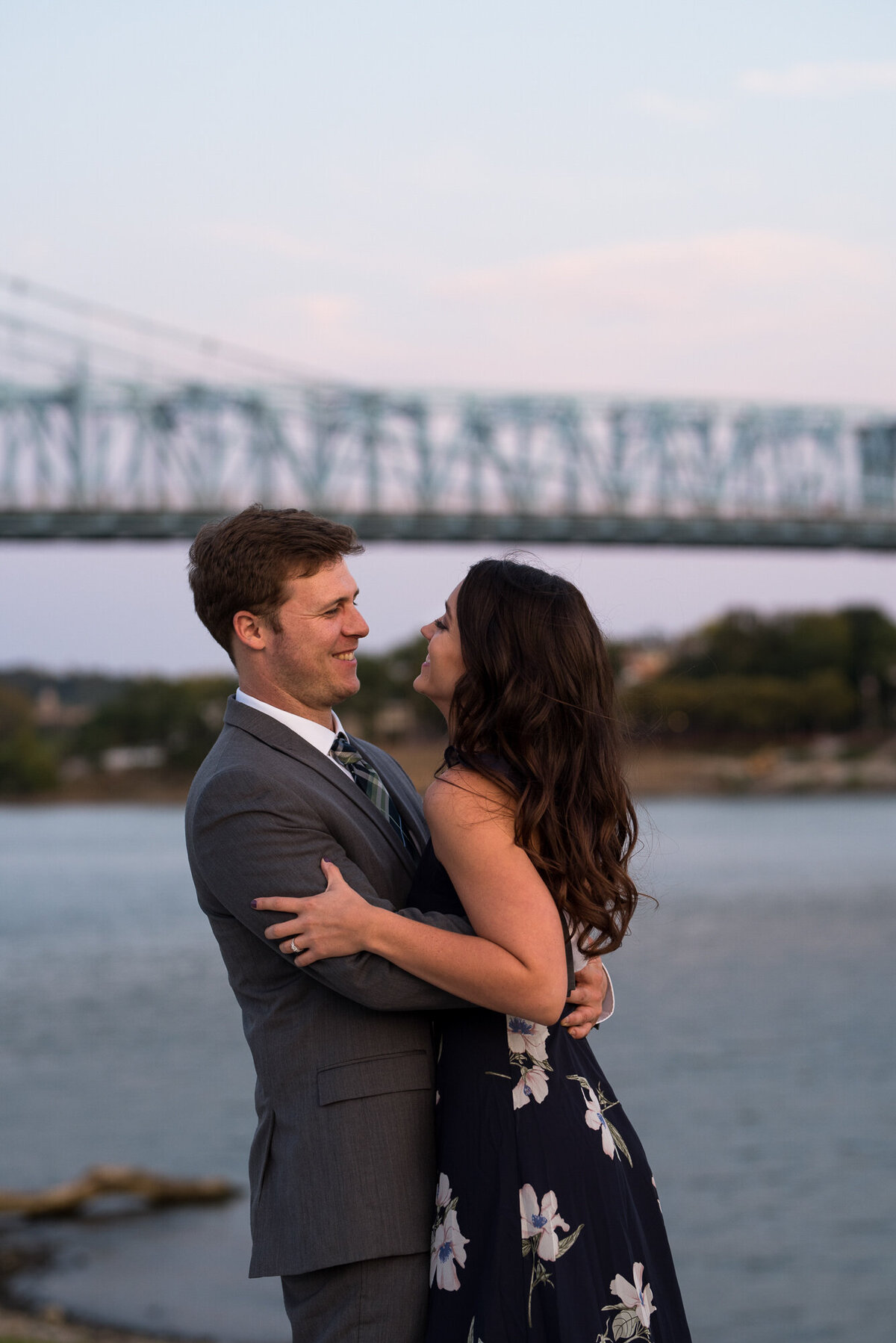 Couple laughs and snuggles in front of the bridge in downtown cincinnati