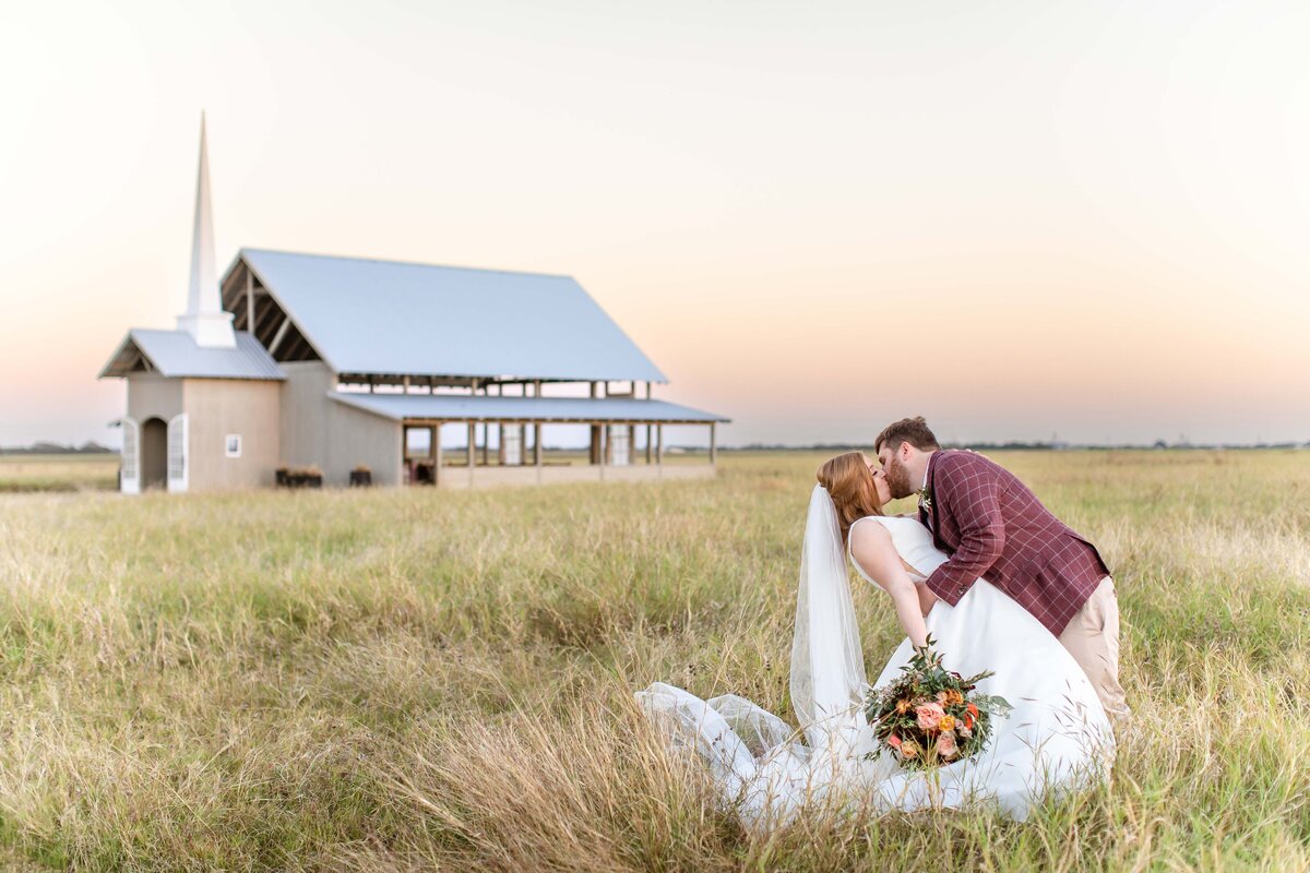 bride and groom kiss at sunset with Allen Farmhaus chapel in background
