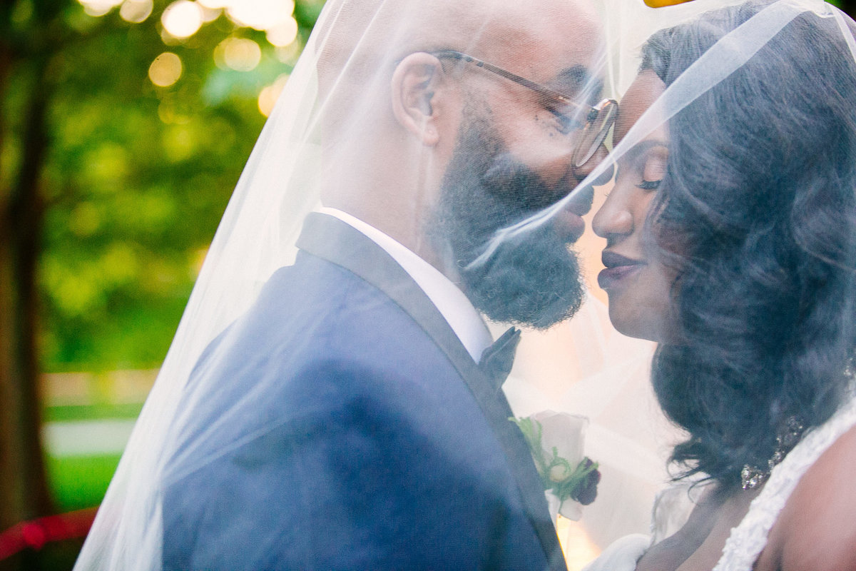 Elegant bride and groom nuzzle each other under the bride’s veil, taken outside the Caramel Room in STL.