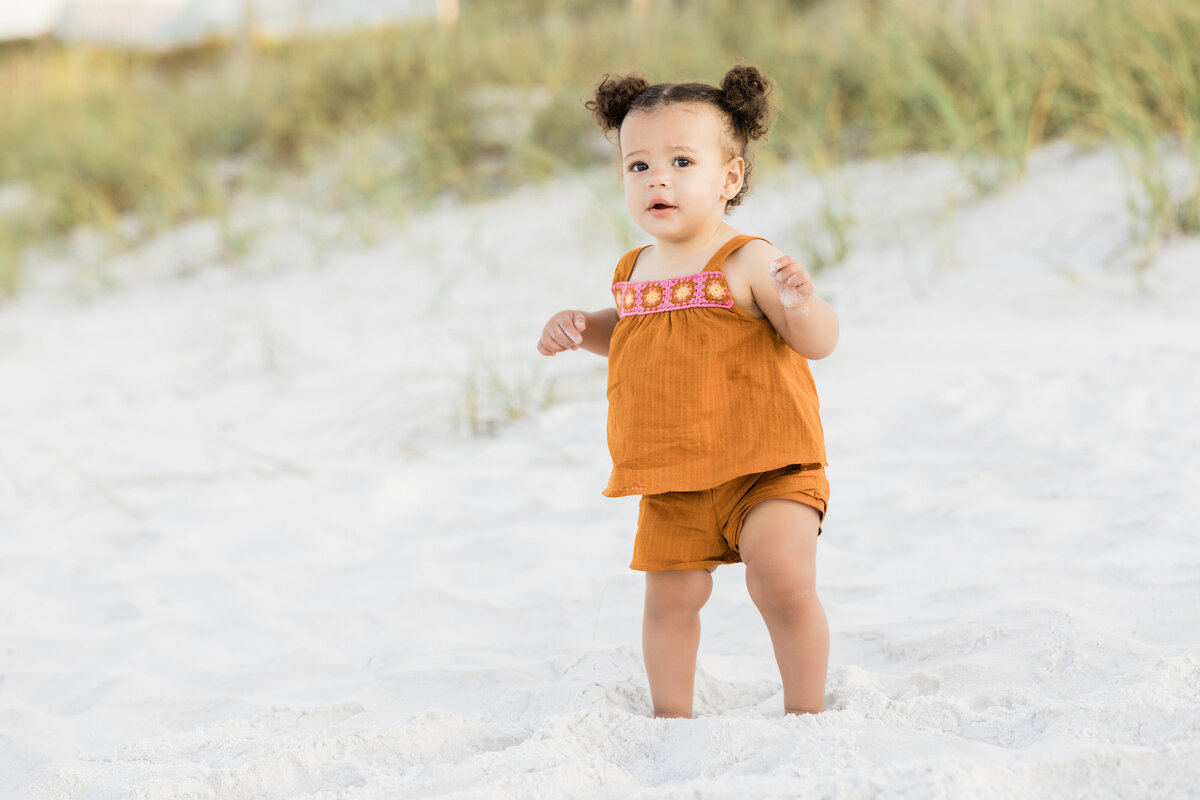 A small child standing in the sand at a beach