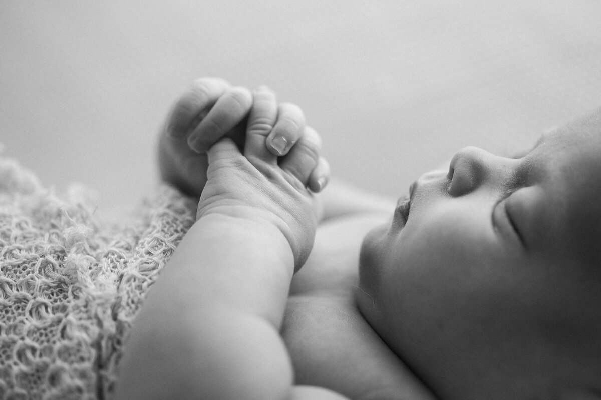 black and white close up photo of baby’s face profile & clasped hands in praying position