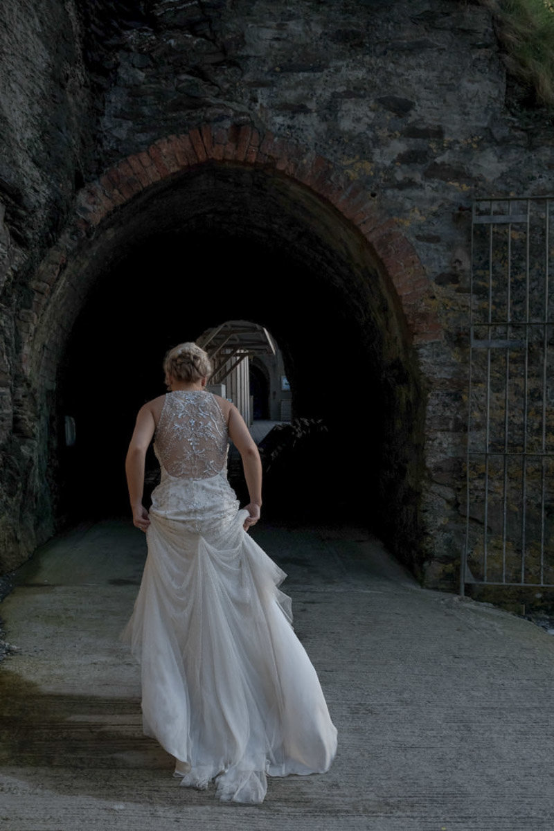 Bride in her wedding dress walking into the tunnel at Tunnels Beaches Devon