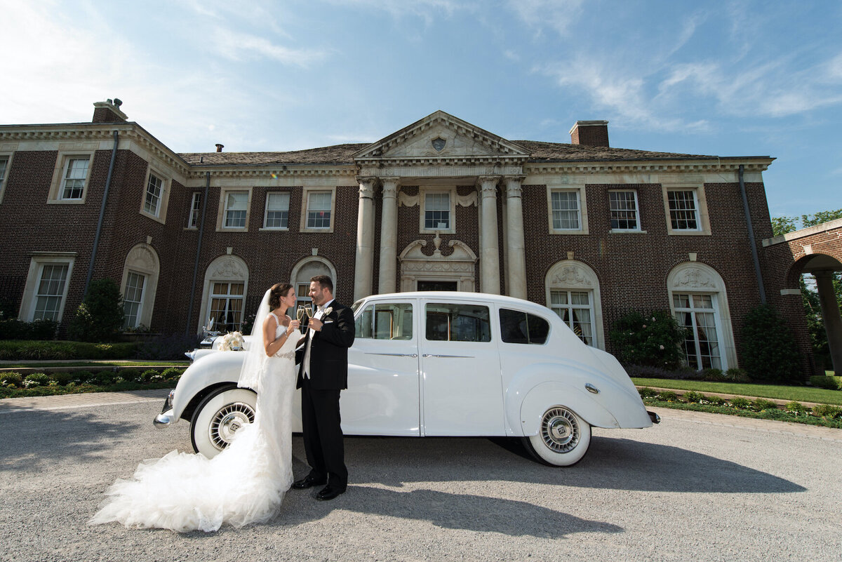 bride and groom standing outside de Seversky Mansion with their car