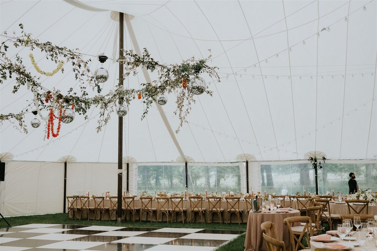 Tented wedding reception in the Hudson Valley with black and white dance floor and disco balls and florals