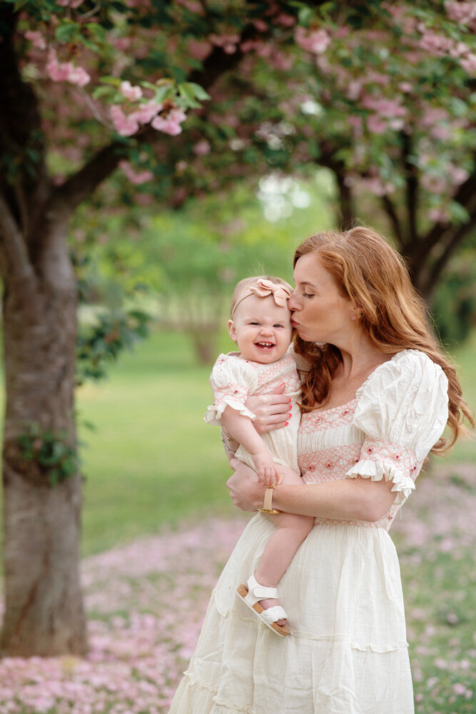 Family session of little girl wearing a bow and her mother outside