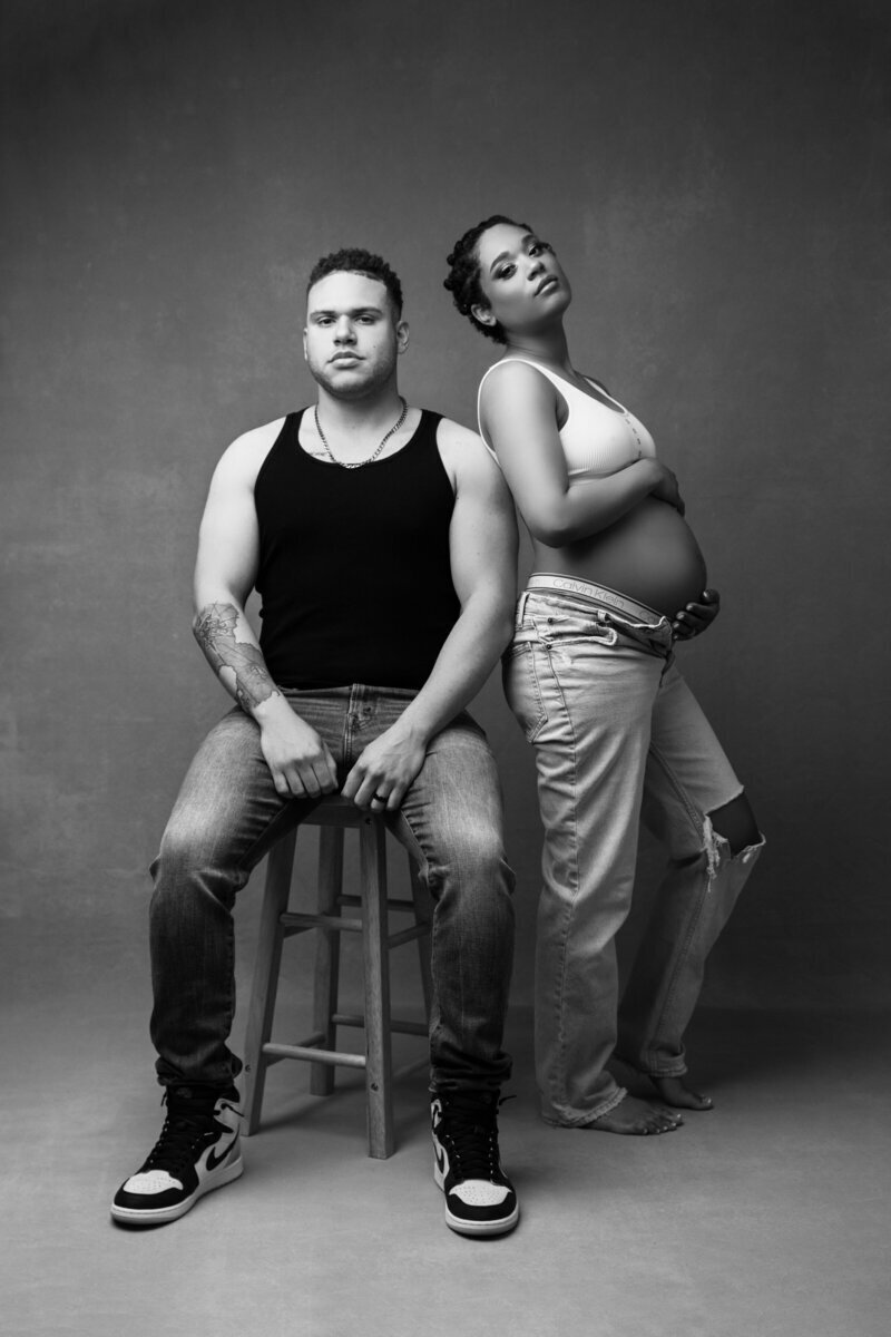 Expecting parents leaning up against each other on stool, by maternity photographer new jersey